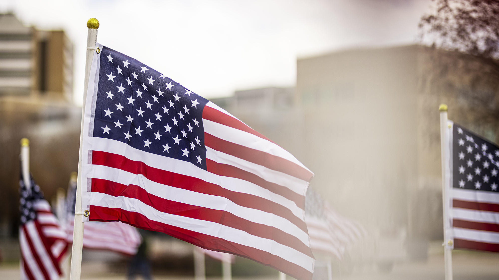 Multiple US flags fly on flagpoles on BYU campus