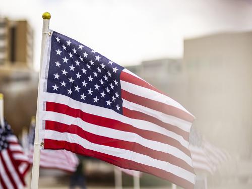 Multiple US flags fly on flagpoles on BYU campus