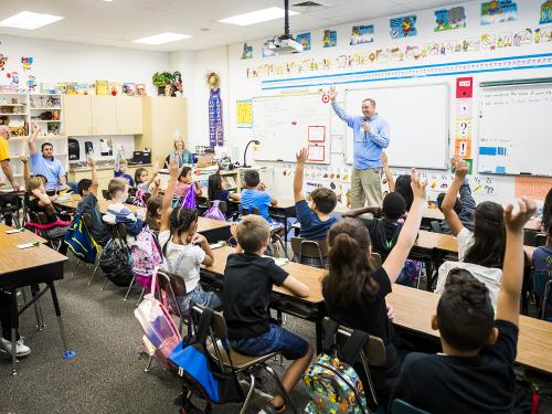 Male teacher in front of an elementary classroom