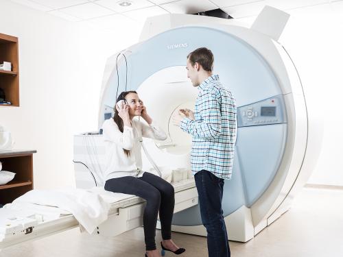 Female sits on an MRI bed talking with standing male