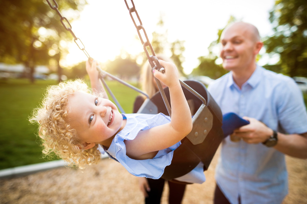 man pushing female child on swing