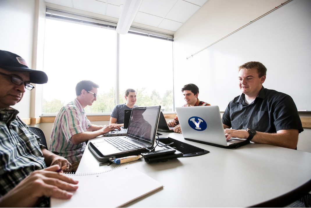 group of males using laptops at a table